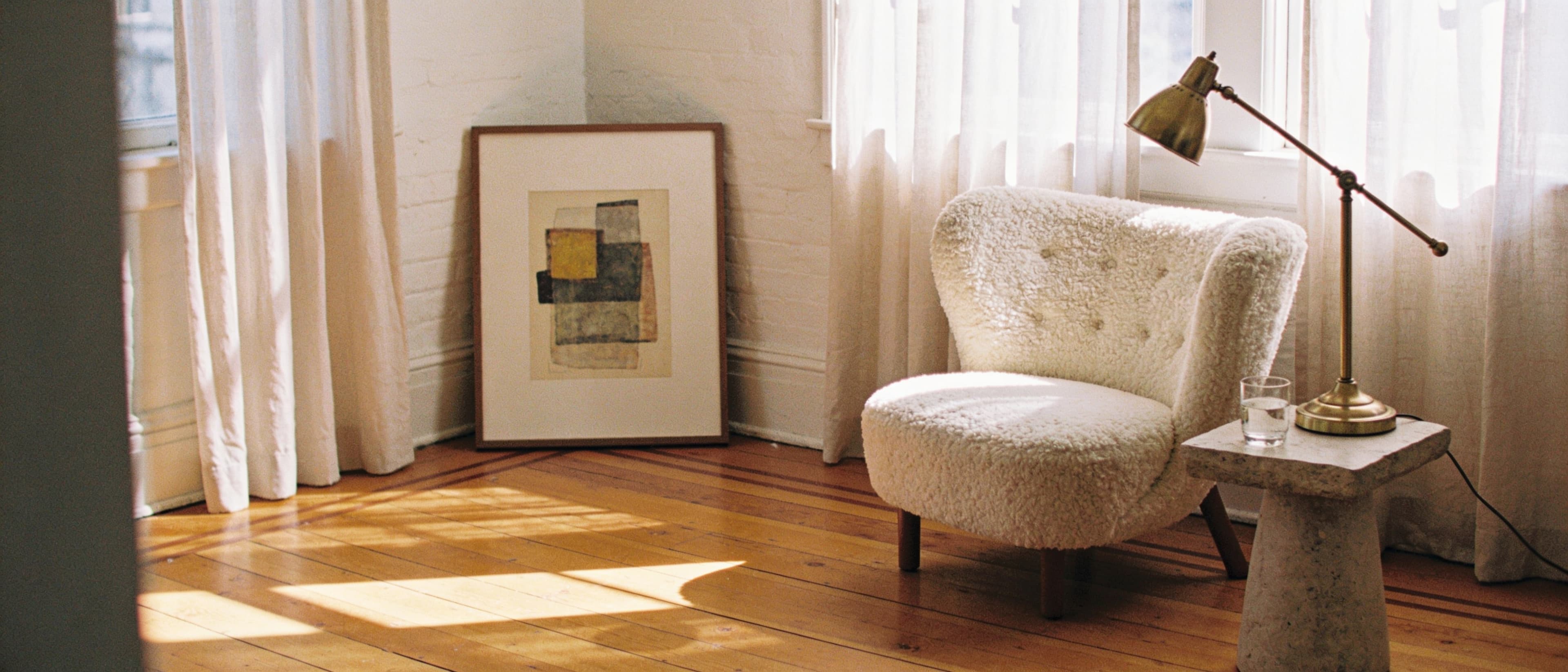 The Anastology studio at ten in the morning — window light across warm plaster, a linen chaise, and pale travertine